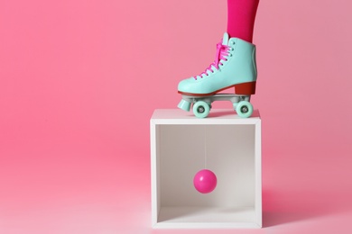 Photo of Woman wearing vintage roller skate and storage cube with ball against color background, closeup. Space for text