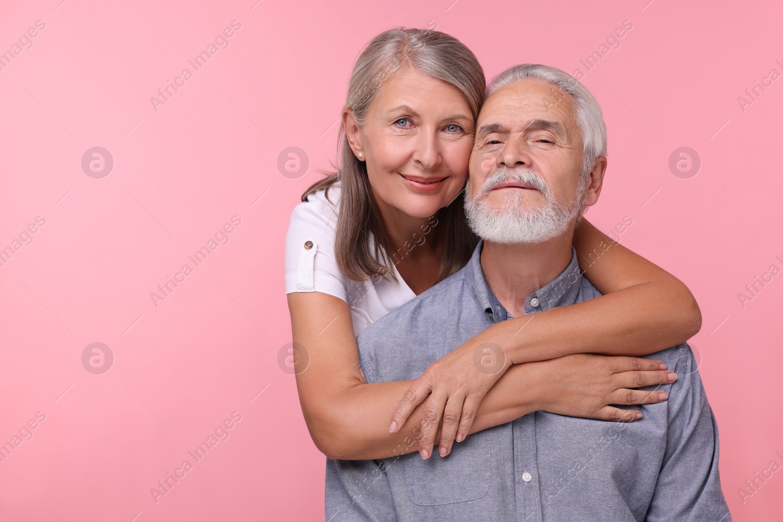 Photo of Portrait of happy affectionate senior couple on pink background, space for text