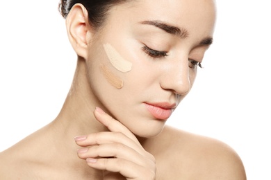 Young woman with different shades of skin foundation on her face against white background