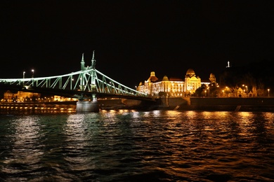 Photo of BUDAPEST, HUNGARY - APRIL 27, 2019: Beautiful night cityscape with illuminated Gellert Hotel and Liberty Bridge across Danube river