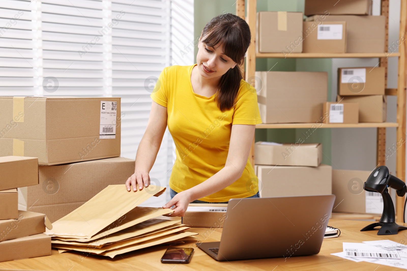 Photo of Parcel packing. Post office worker with parcels at wooden table indoors