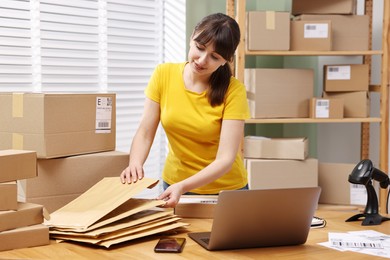 Photo of Parcel packing. Post office worker with parcels at wooden table indoors