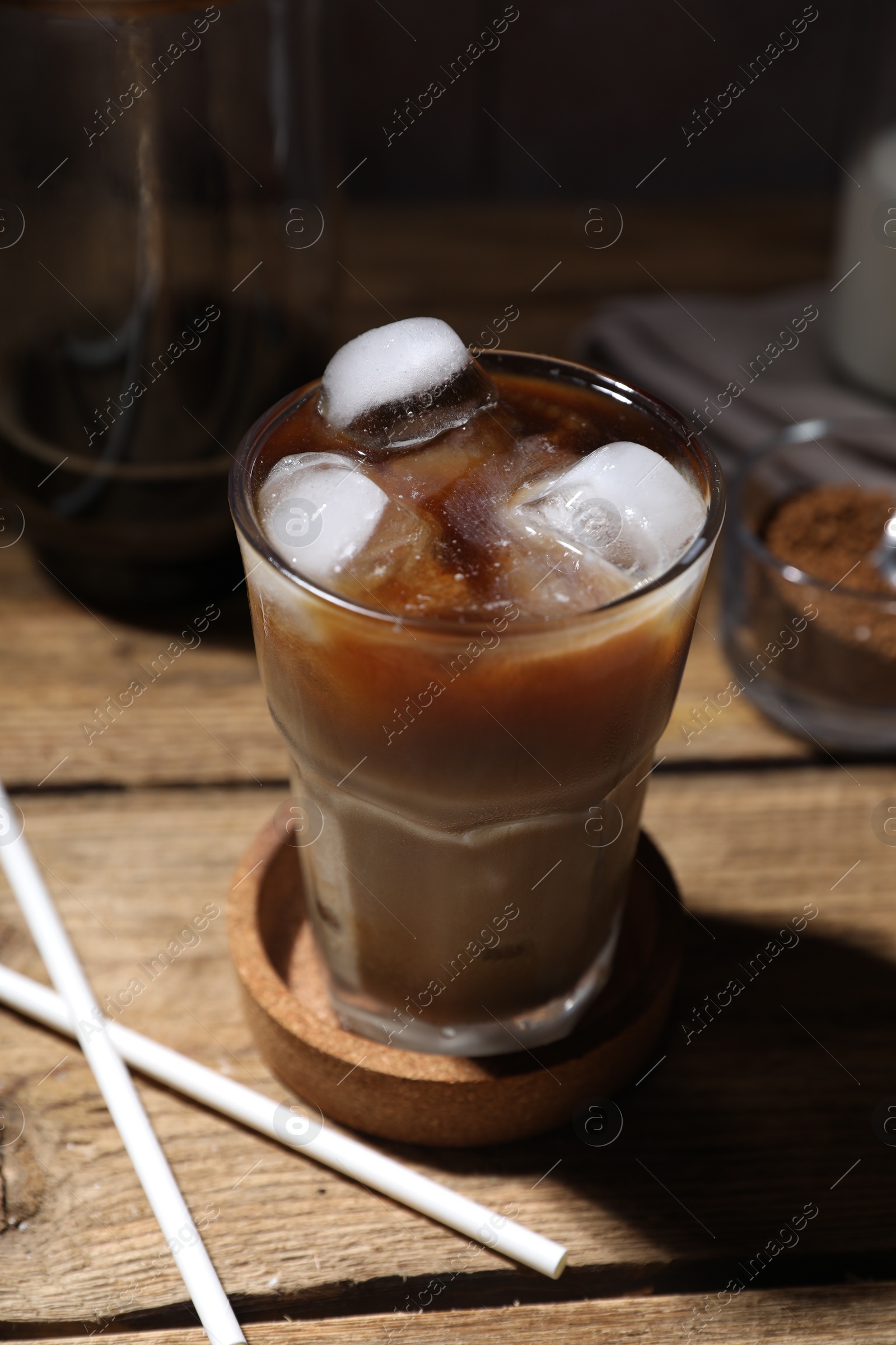 Photo of Refreshing iced coffee in glass and straws on wooden table