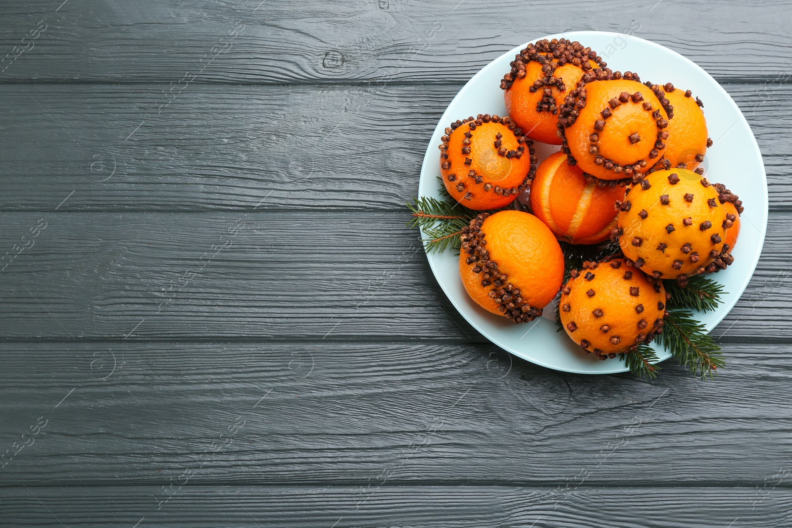 Photo of Pomander balls made of fresh tangerines and cloves on wooden table, top view. Space for text