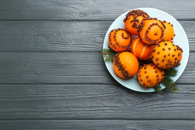 Pomander balls made of fresh tangerines and cloves on wooden table, top view. Space for text