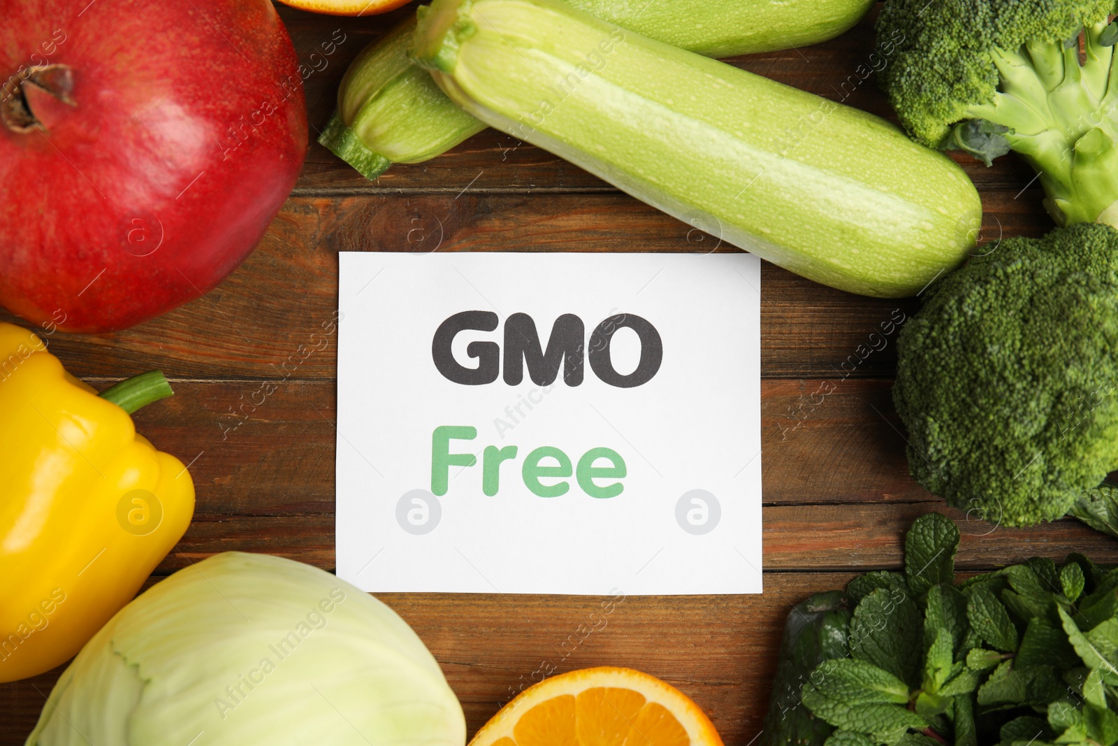 Photo of Tasty fresh GMO free products and paper card on wooden table, flat lay