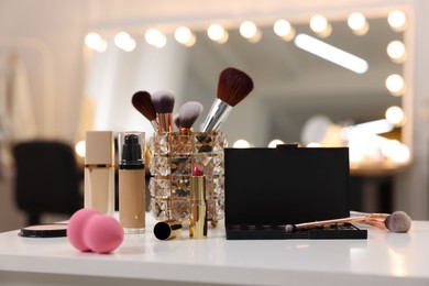 Different cosmetic products on white table in makeup room