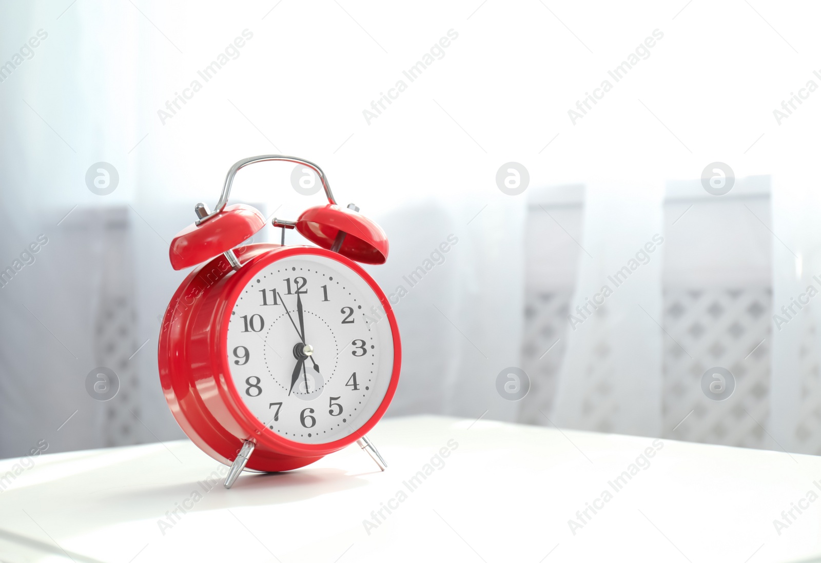 Photo of Analog alarm clock on table indoors. Time of day