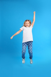 Photo of Cute little girl jumping on light blue background