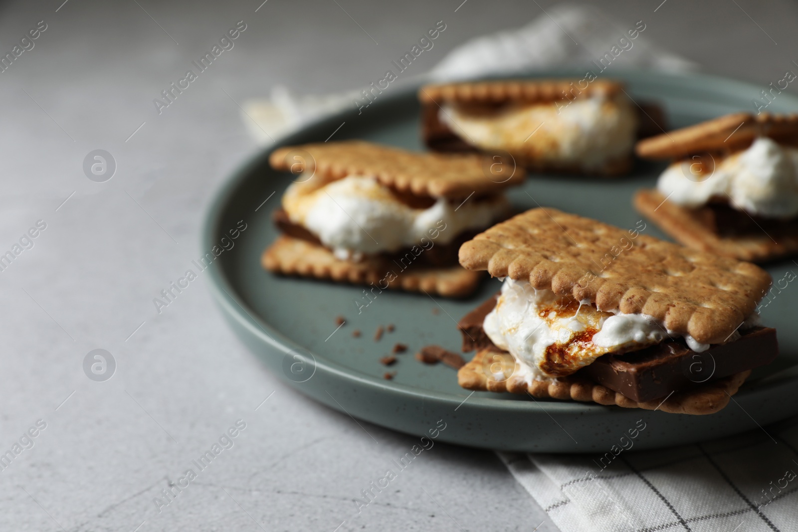 Photo of Delicious marshmallow sandwiches with crackers and chocolate on light grey table, closeup. Space for text