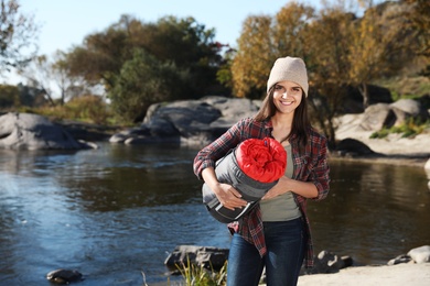 Photo of Female camper with sleeping bag near pond. Space for text