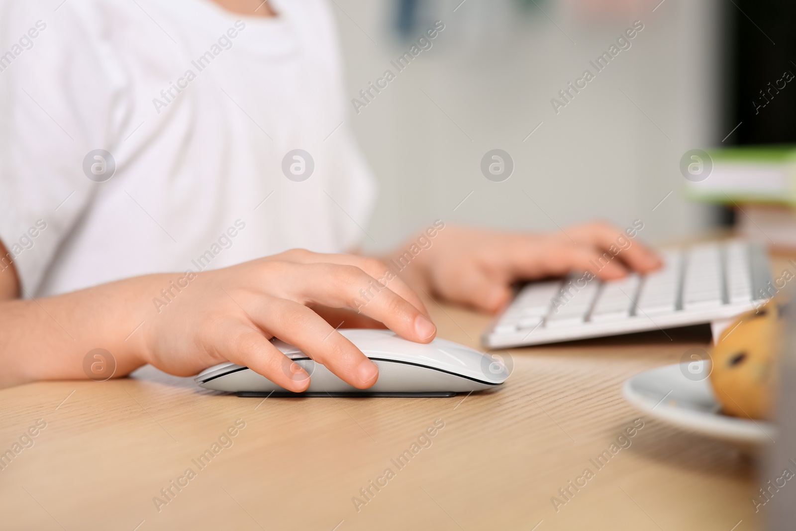 Photo of Little girl using computer at table in room, closeup. Internet addiction