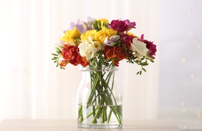 Photo of Beautiful spring bright freesia flowers in vase on table