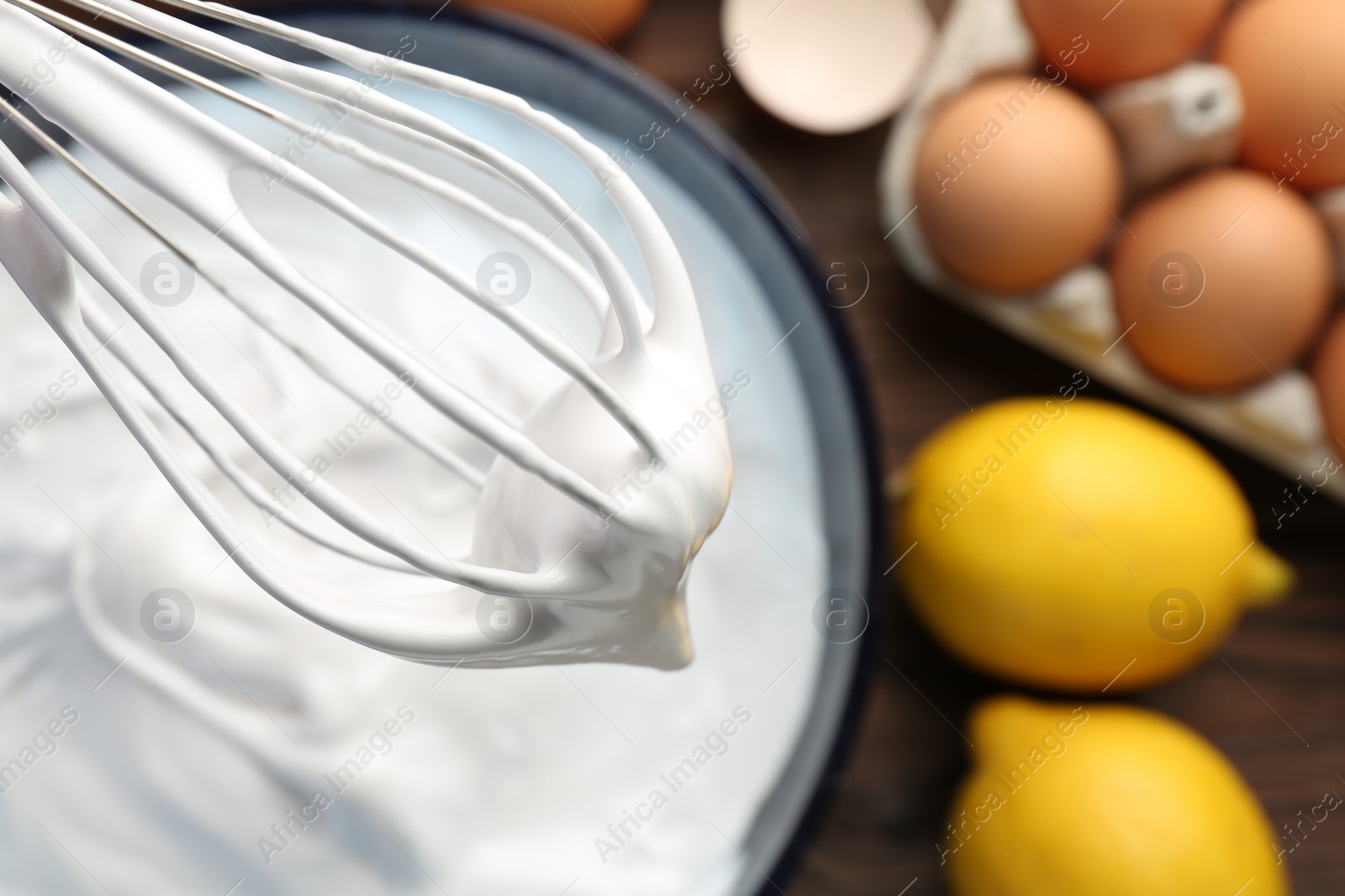 Photo of Whisk with whipped cream over bowl, top view