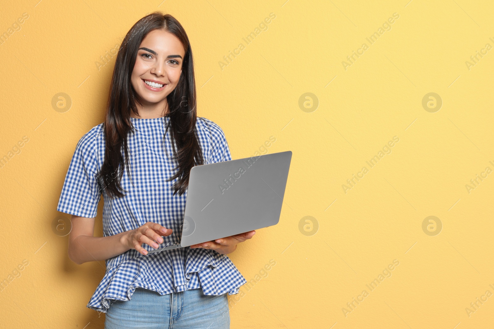 Photo of Young woman with modern laptop on color background