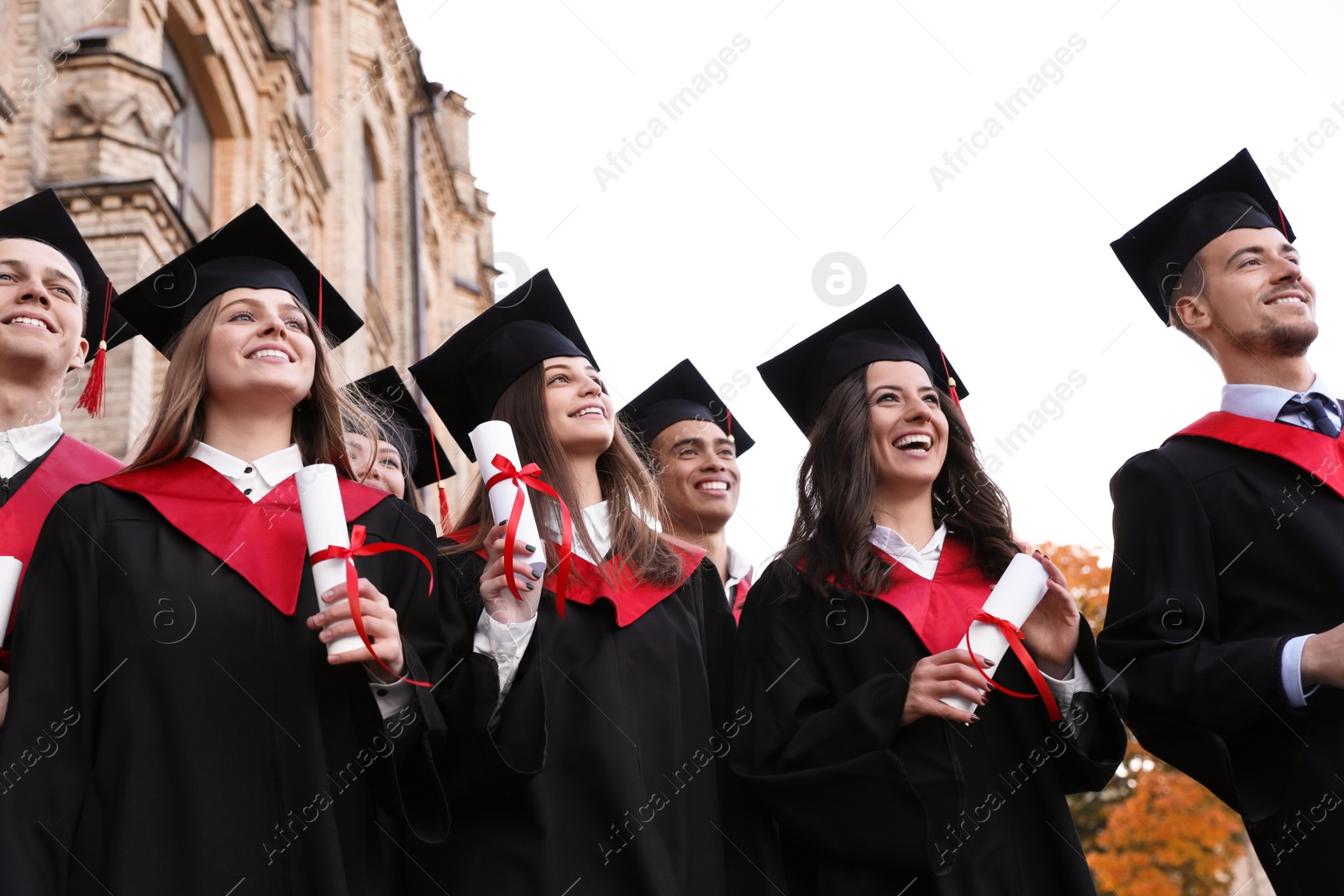 Photo of Happy students with diplomas outdoors. Graduation ceremony