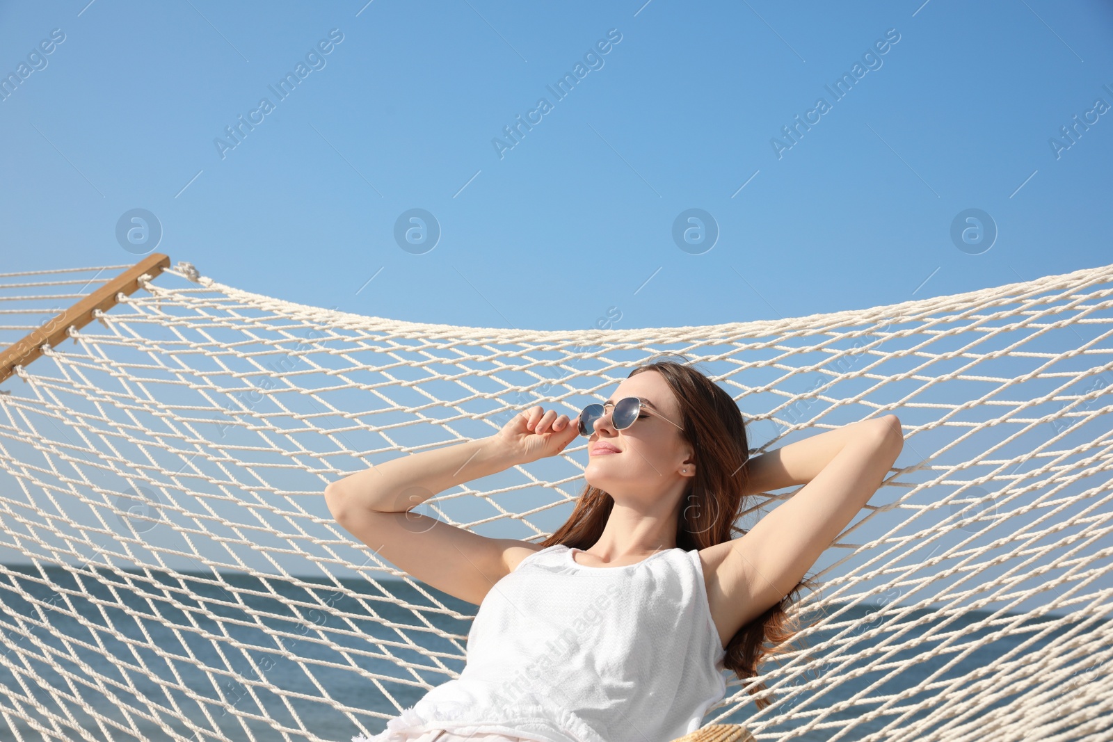 Photo of Young woman relaxing in hammock on beach