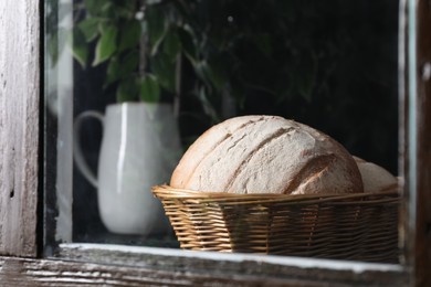 Photo of Fresh homemade bread in wicker basket, view through window