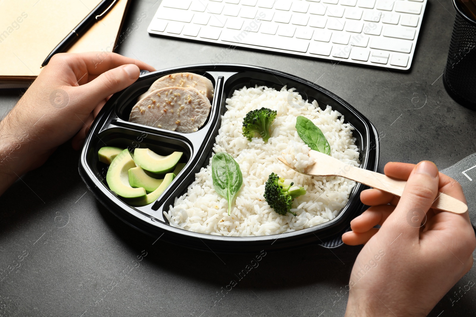 Photo of Man eating natural protein food from container at office table