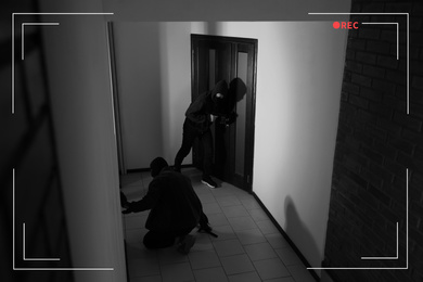 Dangerous criminals with gun and crow bar intruding into apartment, view through CCTV camera