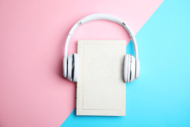 Photo of Book and modern headphones on color background, top view