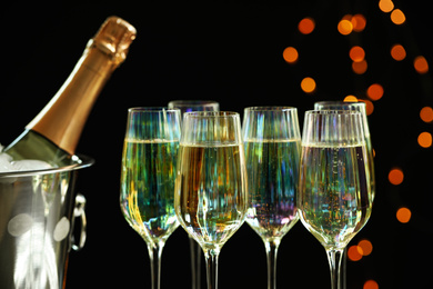 Glasses of champagne and ice bucket with bottle on black background