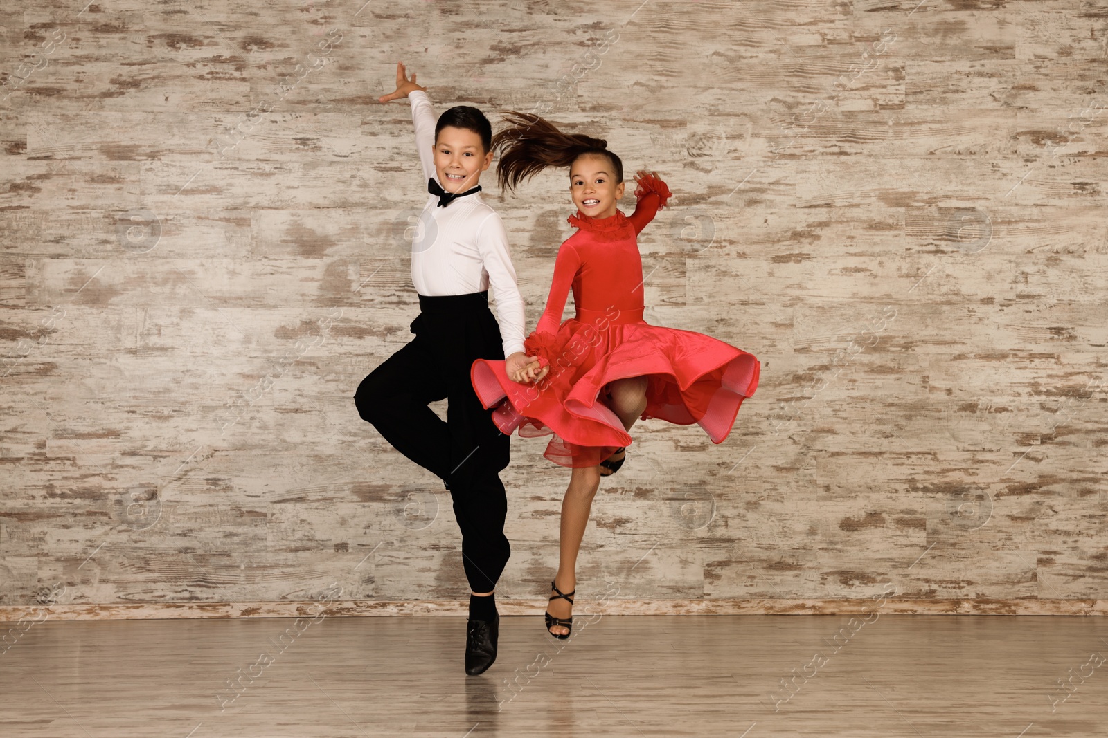 Photo of Beautifully dressed couple of kids dancing together in studio