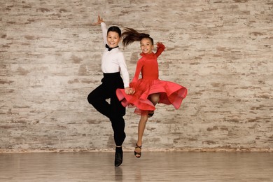 Beautifully dressed couple of kids dancing together in studio