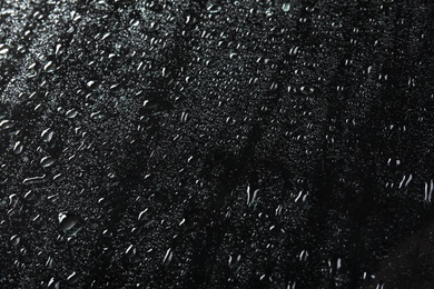 Photo of Glass with rain drops against dark background