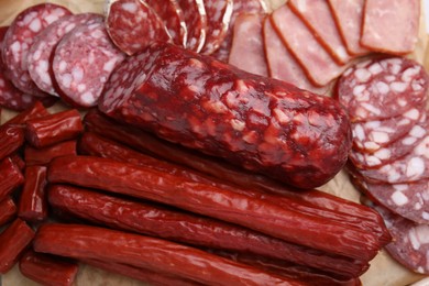 Photo of Different types of delicious sausages and tomatoes on kraft paper, closeup