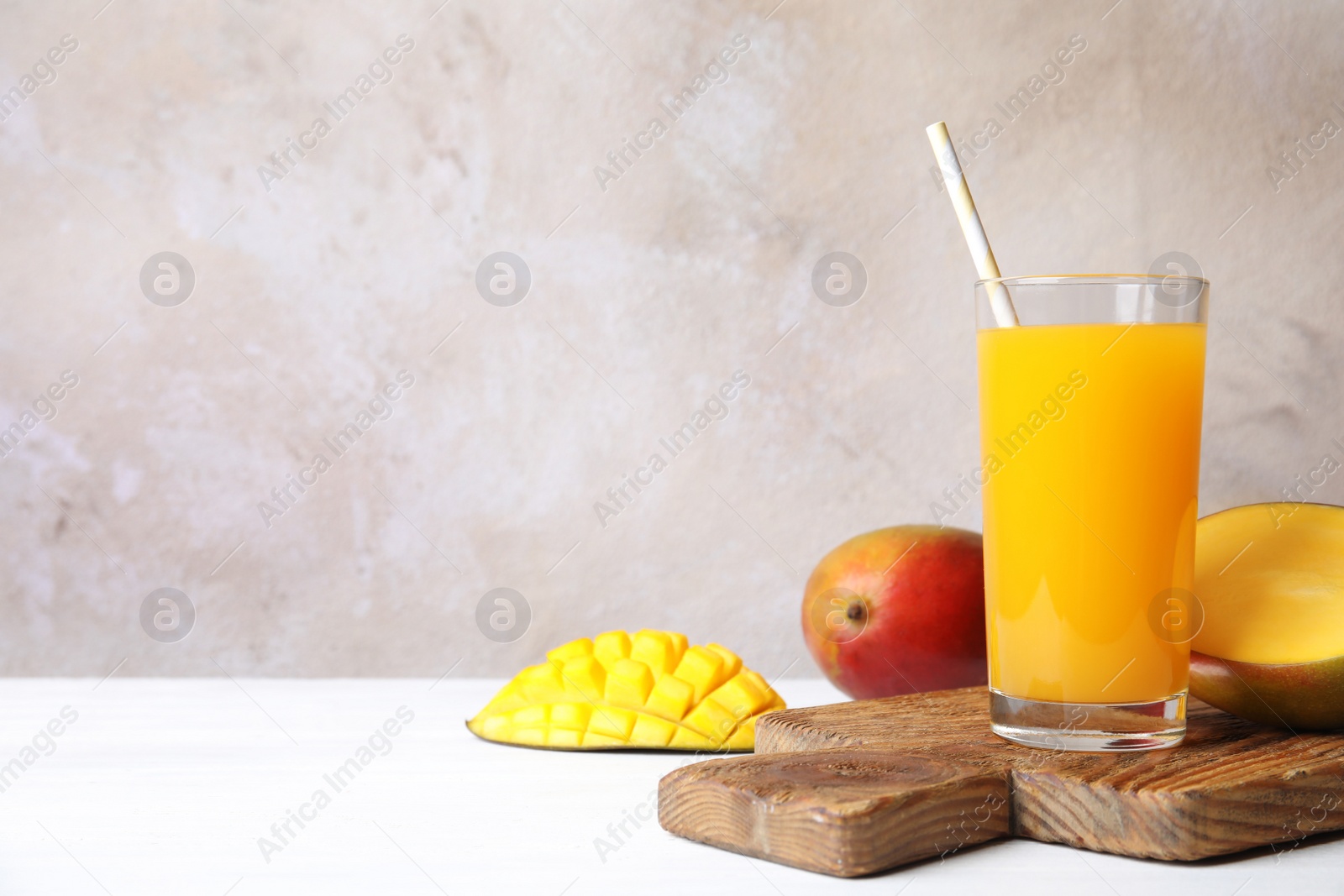 Photo of Glass with fresh mango juice and tasty fruits on table. Space for text