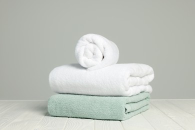 Soft towels on white wooden table against light grey background