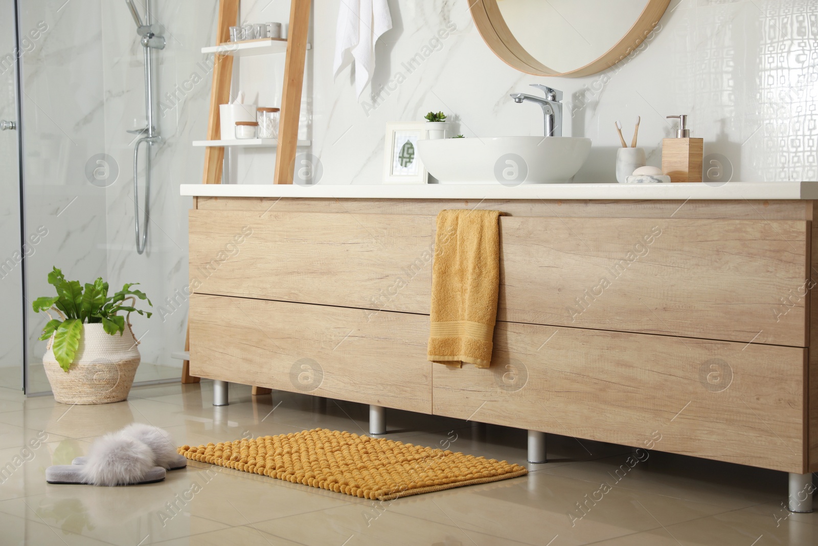 Photo of Soft orange bath mat and slippers on floor in bathroom