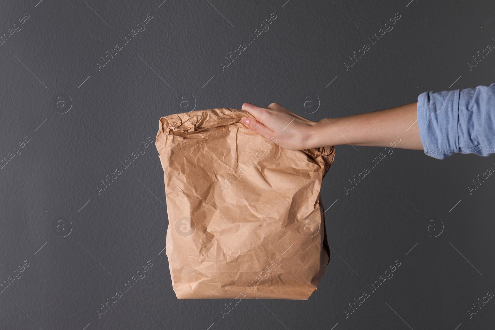 Photo of Woman holding paper bag on dark background. Mockup for design