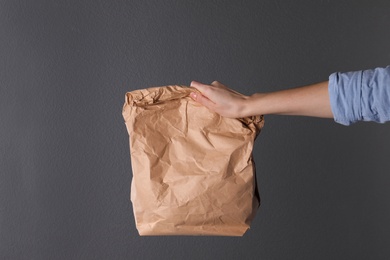 Woman holding paper bag on dark background. Mockup for design