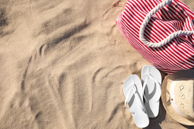 Flat lay composition with different beach accessories on sand. Space for text