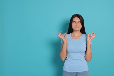 Photo of Young woman meditating on light blue background, space for text. Zen concept