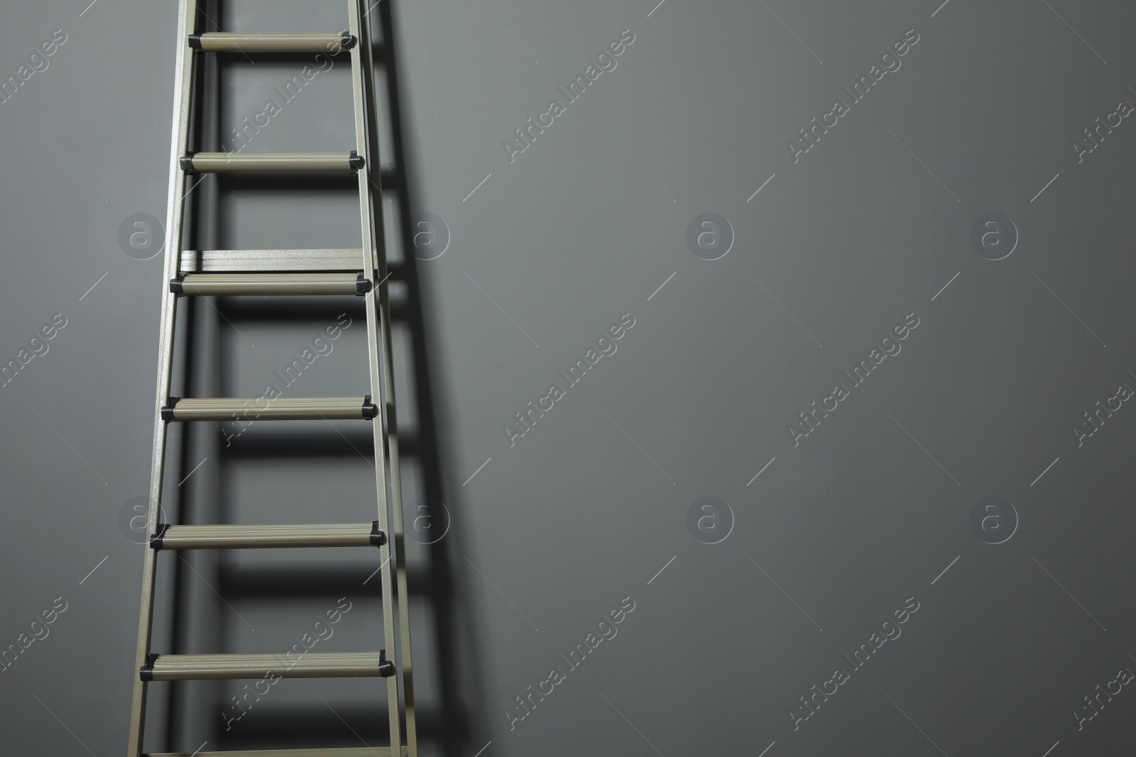 Photo of Metal stepladder on grey background. Space for text