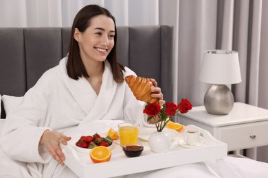 Photo of Smiling woman having breakfast in bed at home