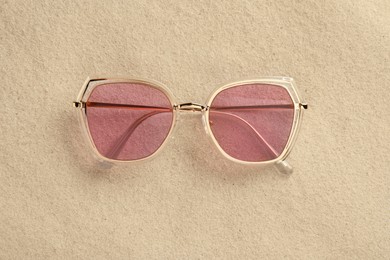 New stylish sunglasses on sand, top view