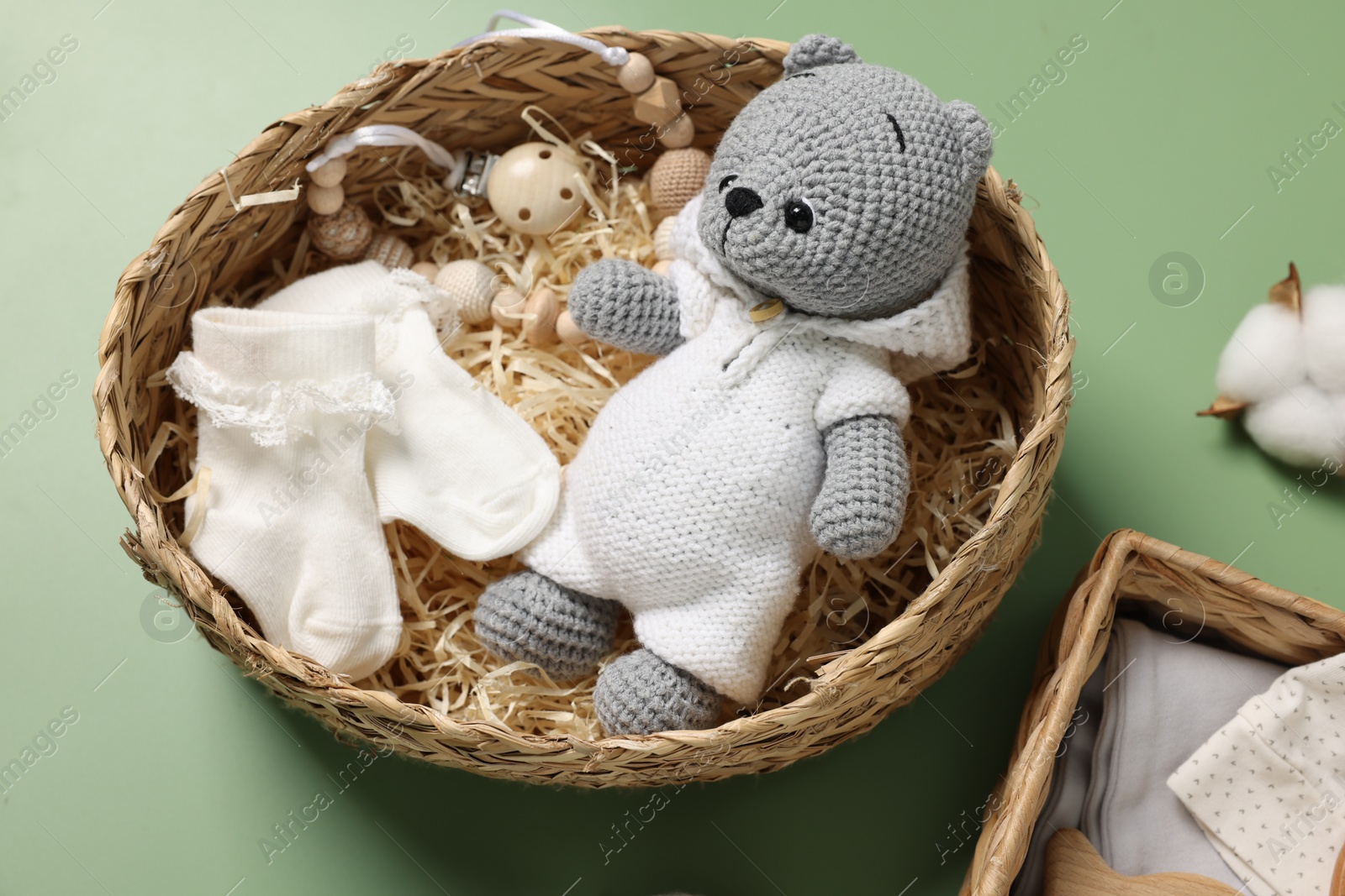 Photo of Different baby accessories in wicker boxes on green background
