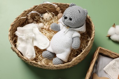 Different baby accessories in wicker boxes on green background