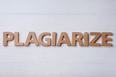 Photo of Word Plagiarize made of wooden letters on white table, flat lay