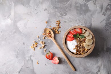 Photo of Tasty granola served on gray textured table, flat lay. Space for text