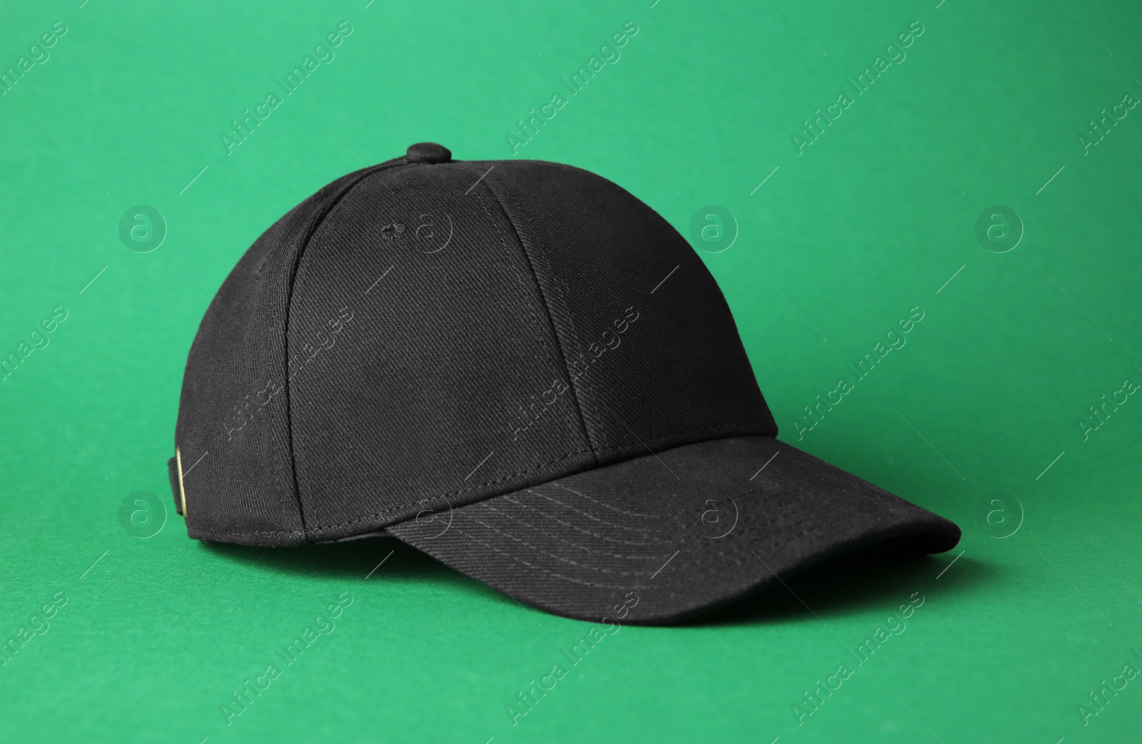 Photo of Stylish black baseball cap on green background