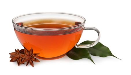 Photo of Glass cup of hot tea with anise stars and green leaves on white background