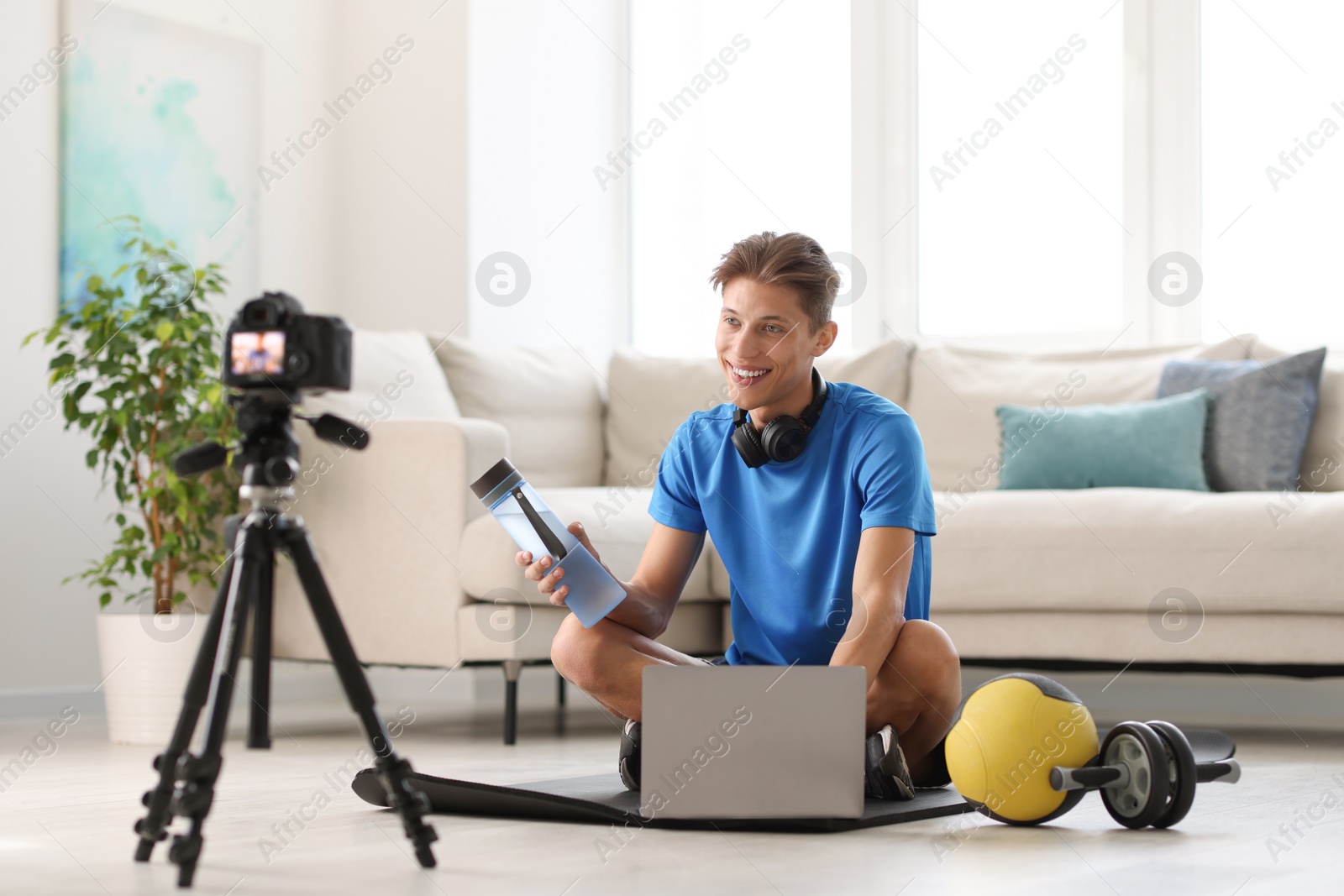 Photo of Smiling sports blogger recording fitness lesson with camera at home