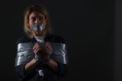 Photo of Woman taped up and taken hostage on dark background. Space for text