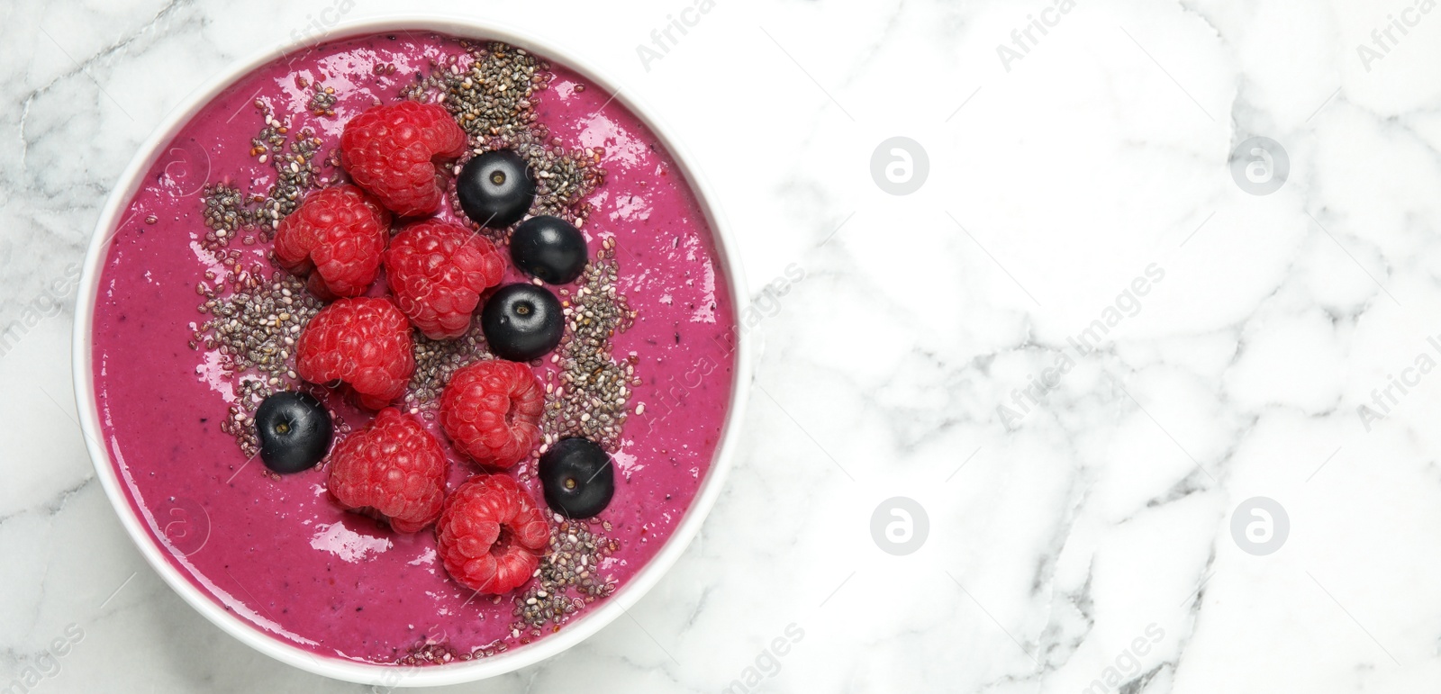 Photo of Delicious acai smoothie with raspberries and chia seeds on white marble table, top view. Space for text