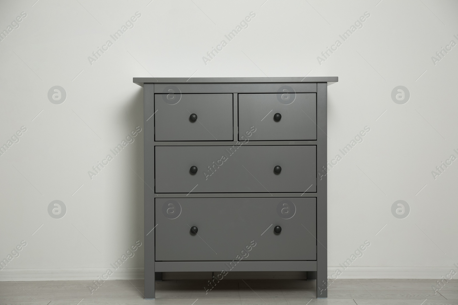 Photo of Grey chest of drawers near light wall